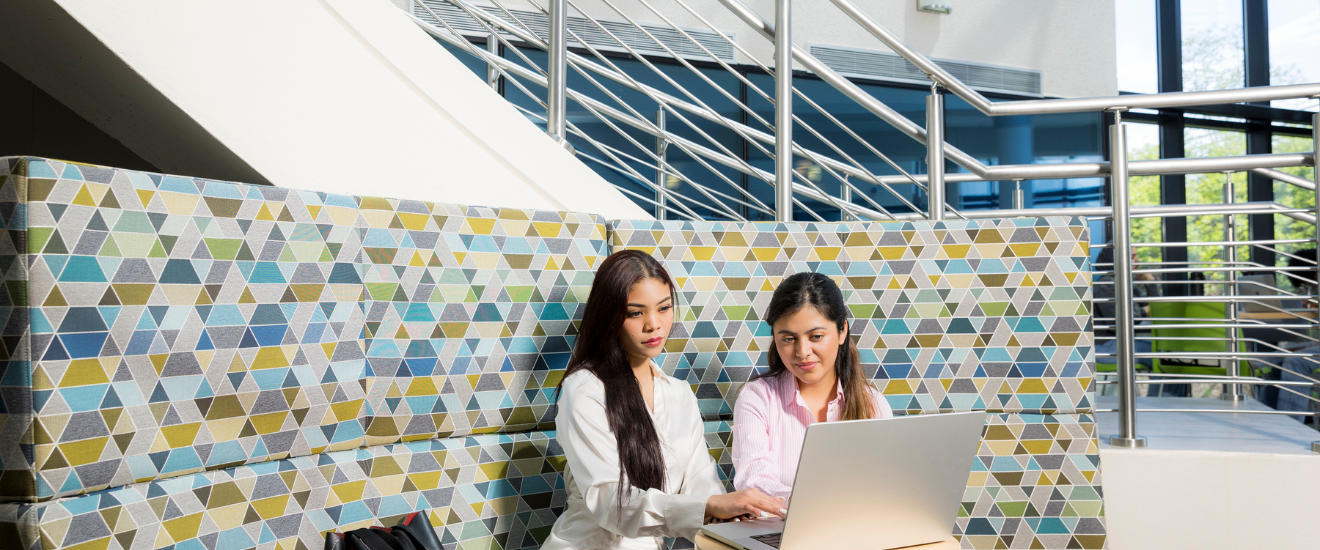 Two female students studying with their laptops on campus